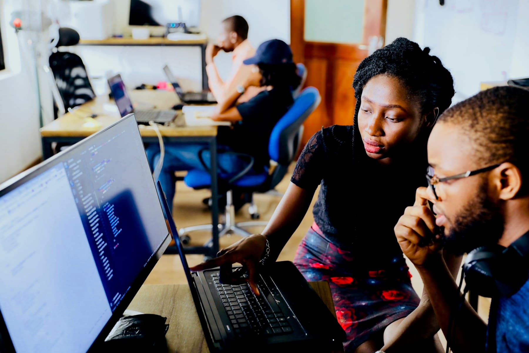 Two colleagues reviewing code and designs on dual screens
