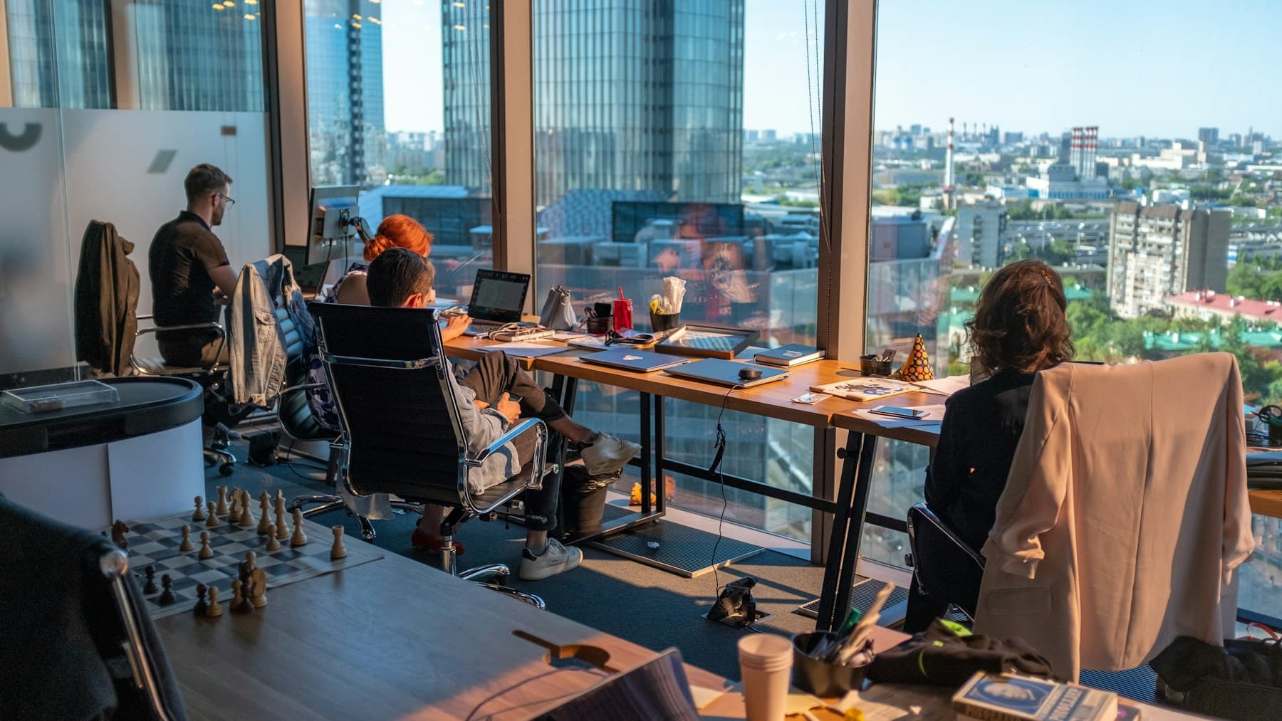 Team working along a long desk by floor-to-ceiling city windows