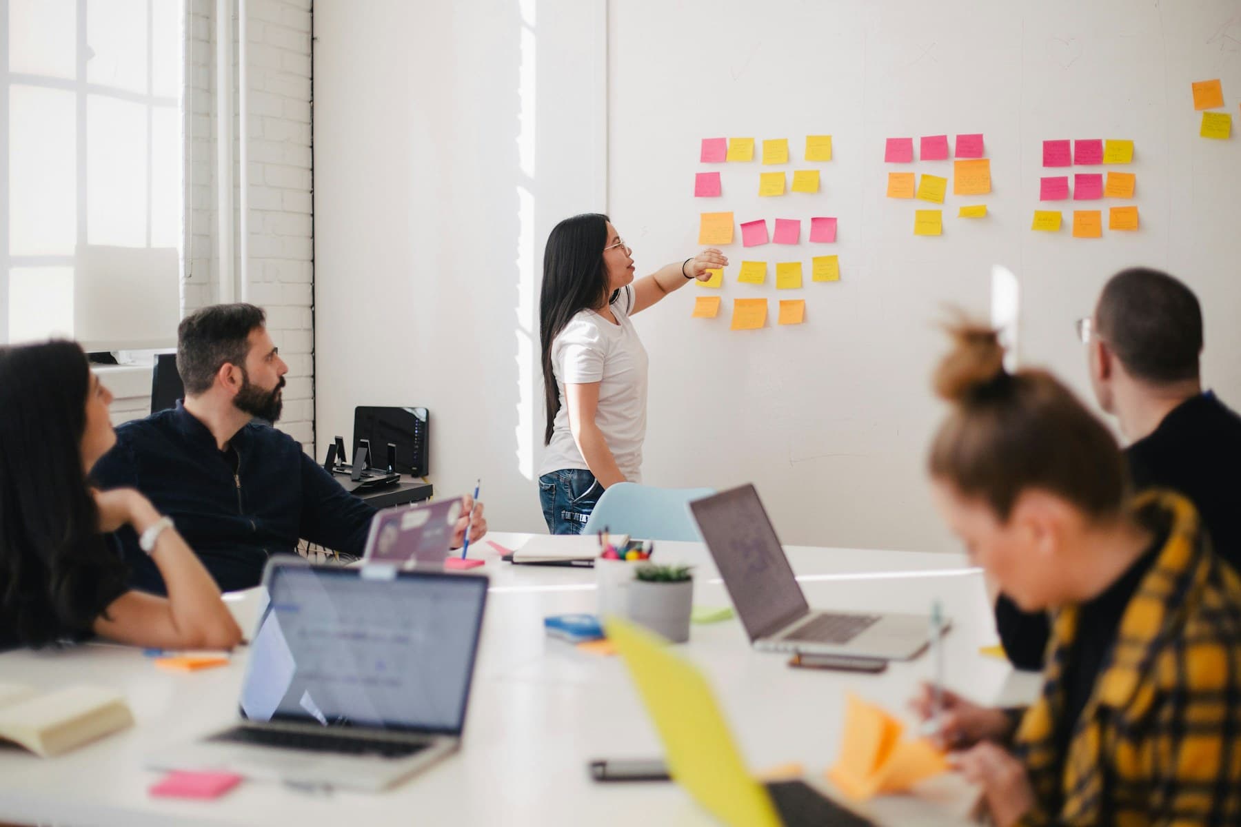Team in a bright white studio reviewing sticky notes on the wall